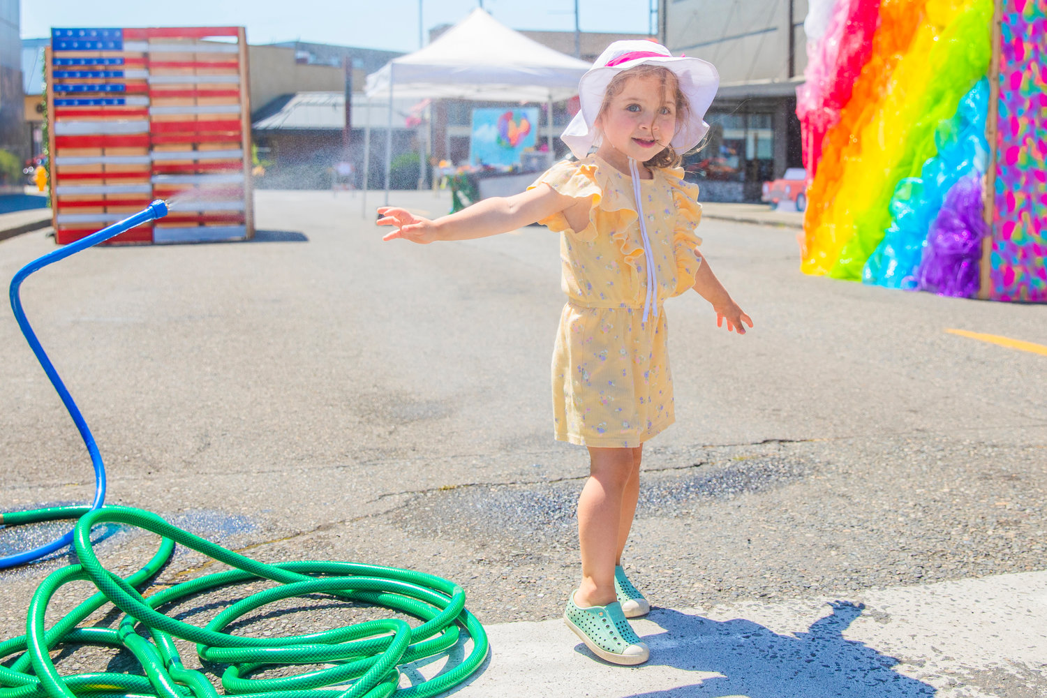 Evie Alderman, 3, smiles while cooling off in a mister during Chehalis Fest on Saturday.